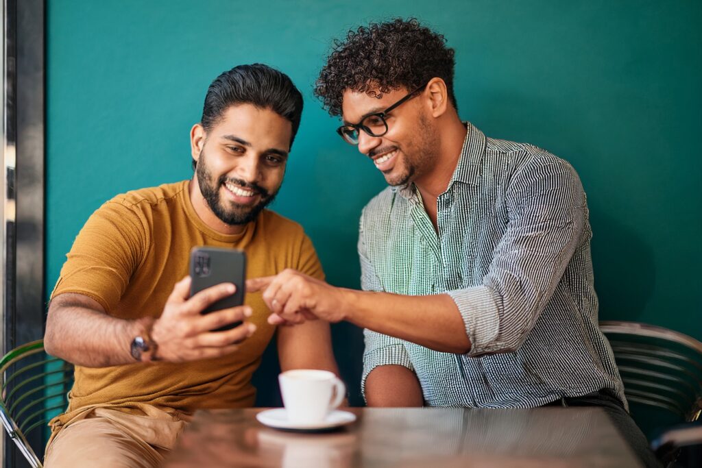 Two men looking at a phone in a coffee shop